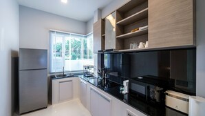 Une cuisine moderne avec un réfrigérateur en acier inoxydable, un plan de travail noir et des étagères en bois.