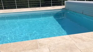 A clear blue pool with tiled edges and a tiled deck area.