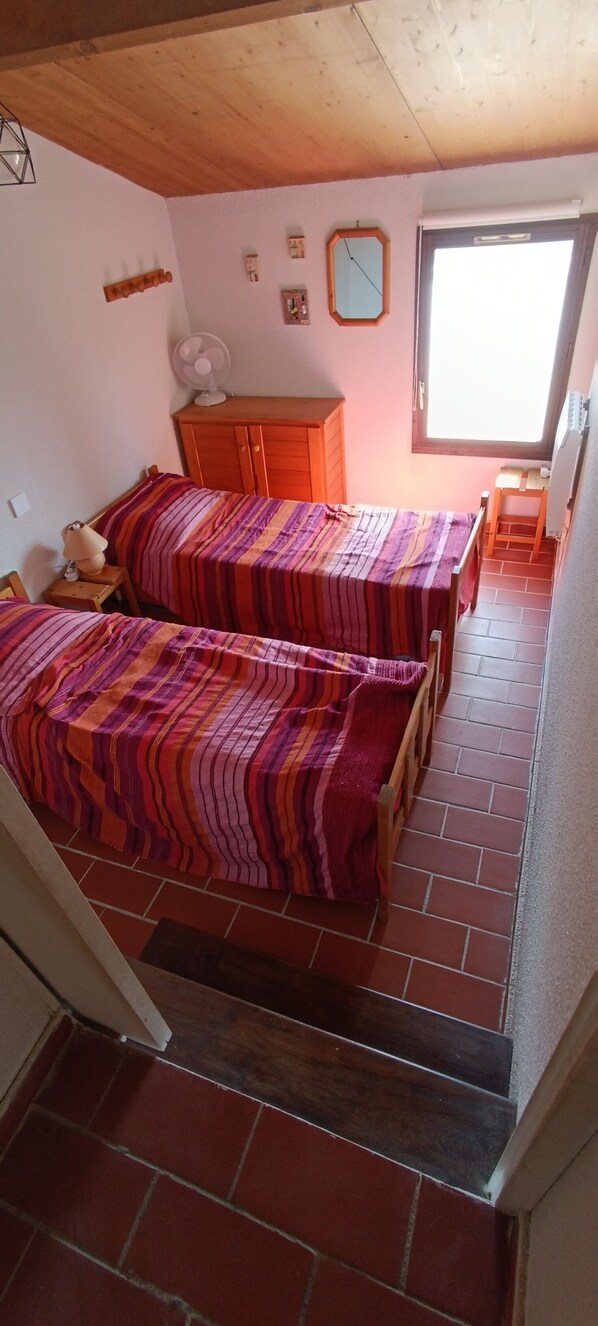 A room with two beds, a wooden cabinet, a fan, and a window. - Peace and relaxation assured, view of the Massif des Maures, 3 bedrooms, private pool. (La Londe-les-Maures)