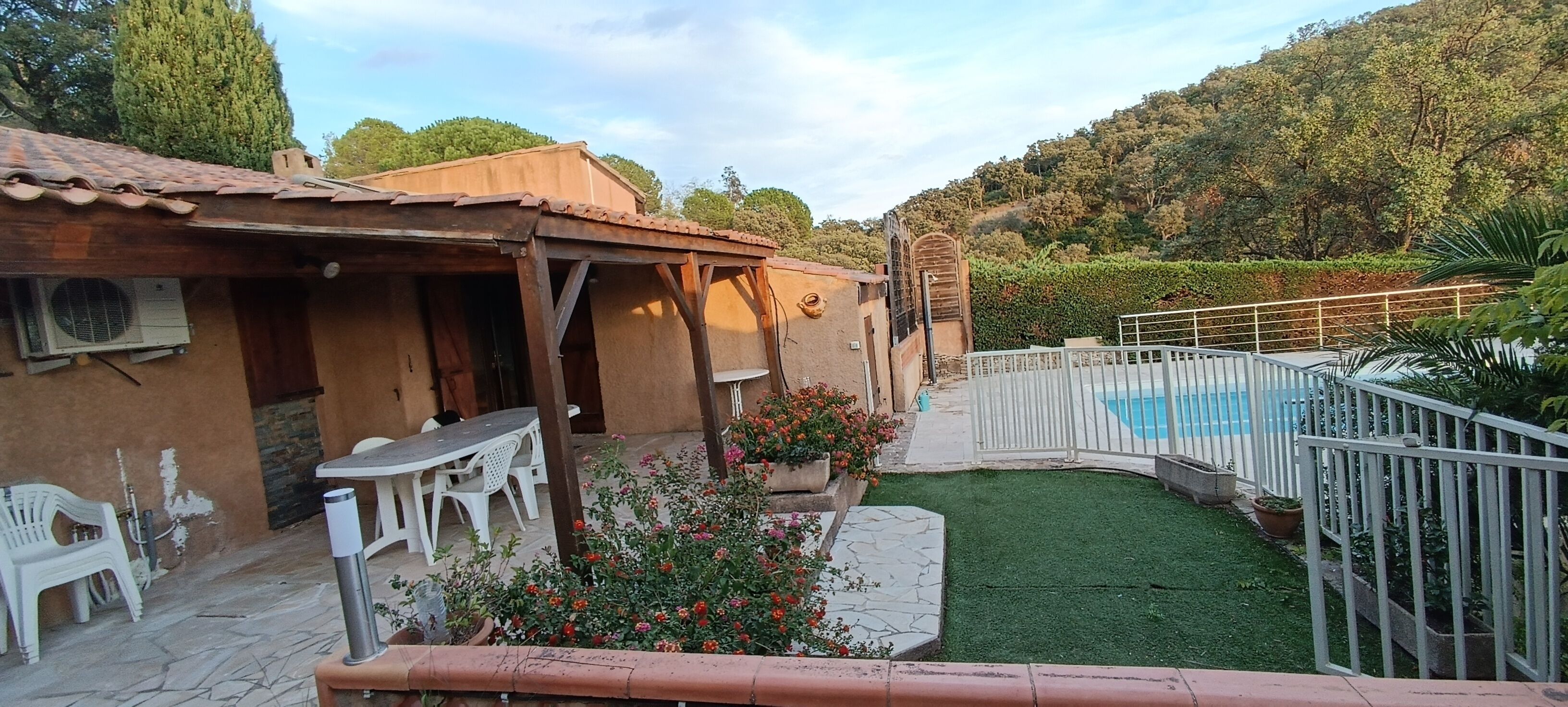 Un espace patio avec une table et des chaises, une petite piscine et un jardin clôturé.