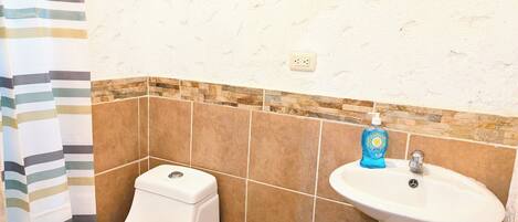 A bathroom with a toilet, a sink, and a shower curtain.