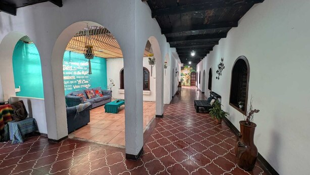 A corridor with arches, a sofa, and a potted plant. - Casa Quetzalli Los Nazarenos (Antigua Guatemala)