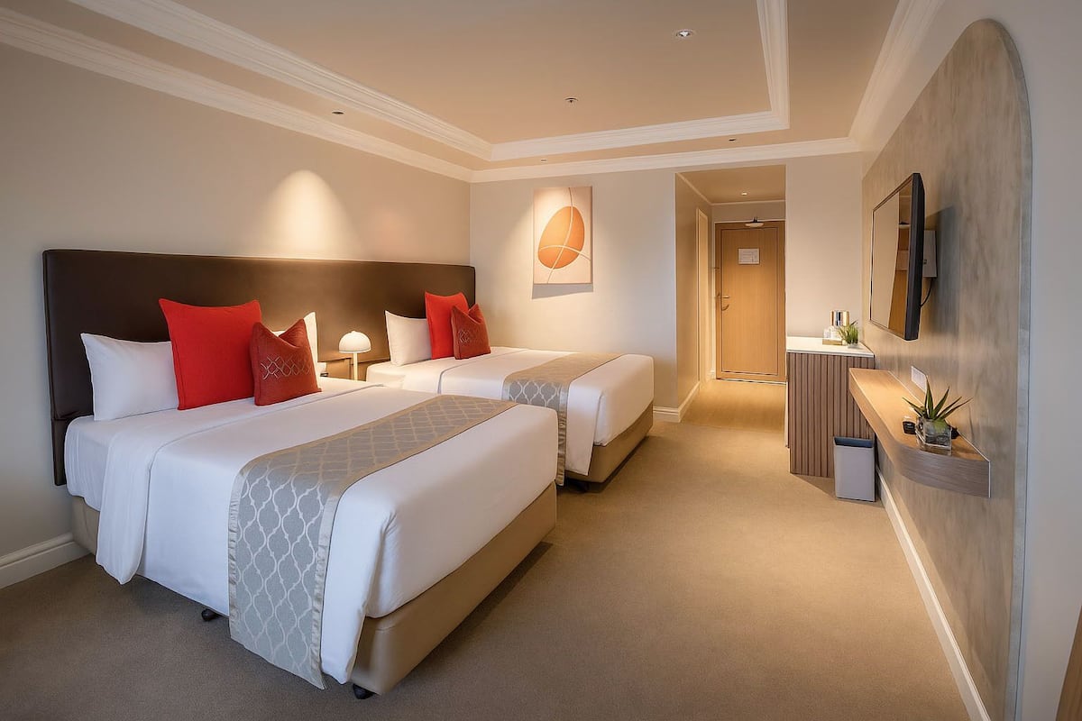 Une chambre d’hôtel avec deux lits, un bureau, un miroir et un espace réception.