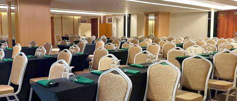 Un salón de conferencias con filas de mesas y sillas, equipado con tarjetas de identificación y elementos de mesa.