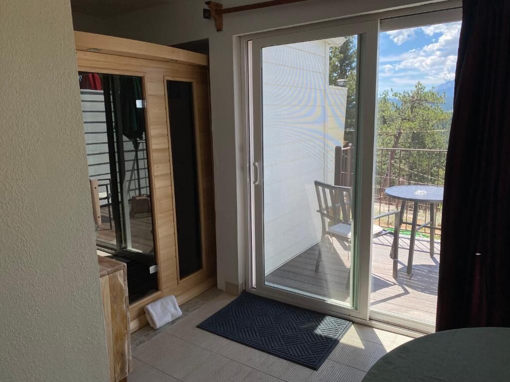 Una habitación con puerta de vidrio corredera que da a un balcón con mobiliario exterior.