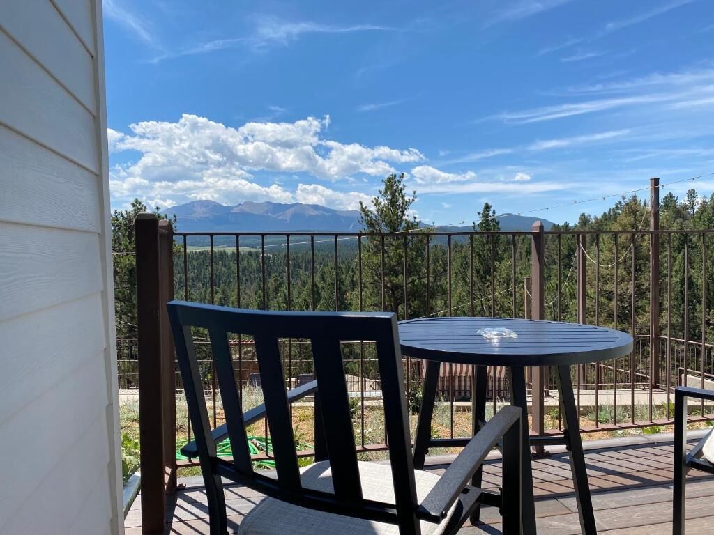 Eine Terrasse mit Tisch und Stühlen mit Blick auf eine gebirgige Landschaft.