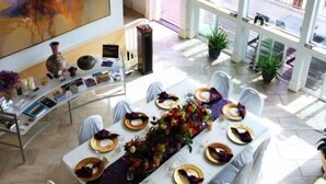 A dining area with a table set for six, white tablecloths, and a colorful centerpiece. - Pikes Peak Paradise Bed and Breakfast (Woodland Park)
