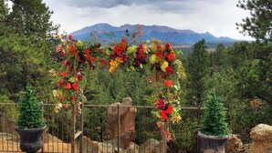 A floral archway with potted plants on either side, set against a mountainous backdrop. - Pikes Peak Paradise Bed and Breakfast (Woodland Park)