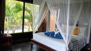 Un dormitorio con cama a dosel, ventanas amplias y vistas a palmeras.