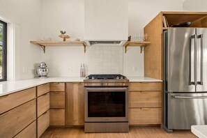 Cozinha moderna com armários de madeira, geladeira de aço inoxidável e forno embutido.