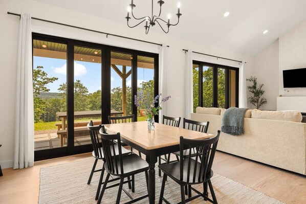 A modern interior with a dining area, a sofa, and a TV.