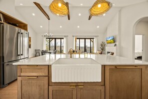 Cozinha moderna com uma ilha grande, eletrodomésticos de aço inoxidável e vista para o exterior.