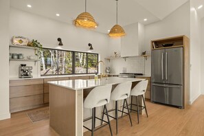 A modern kitchen with a large island, stainless steel appliances, and a view of the outdoors.