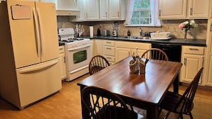 Una cocina con armarios blancos, una mesa de comedor de madera y una estufa.