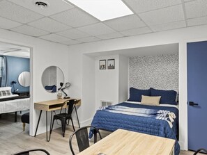 A modern bedroom with a bed, desk, chair, and a small table.