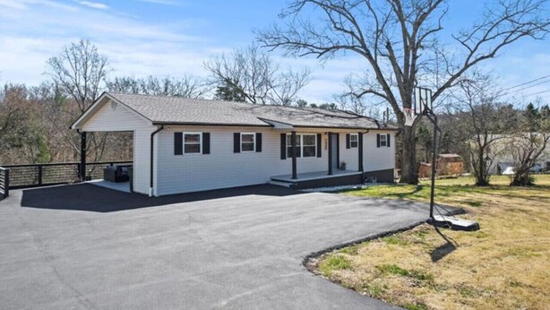 A single-story house with a covered porch, a driveway, and a lawn.