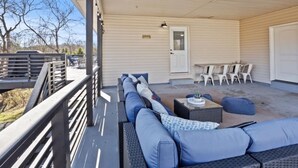 A covered patio with a long sofa, a small table, and chairs.