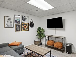 A modern living room with a grey sofa, a coffee table, a flat-screen TV, and decorative items on the wall.