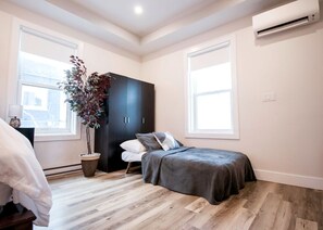 Ein Schlafzimmer mit Bett, Kleiderschrank, Blumentopf und Fenster.