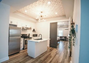 Una cocina moderna con armarios blancos, una isla central y un diseño geométrico en el techo.