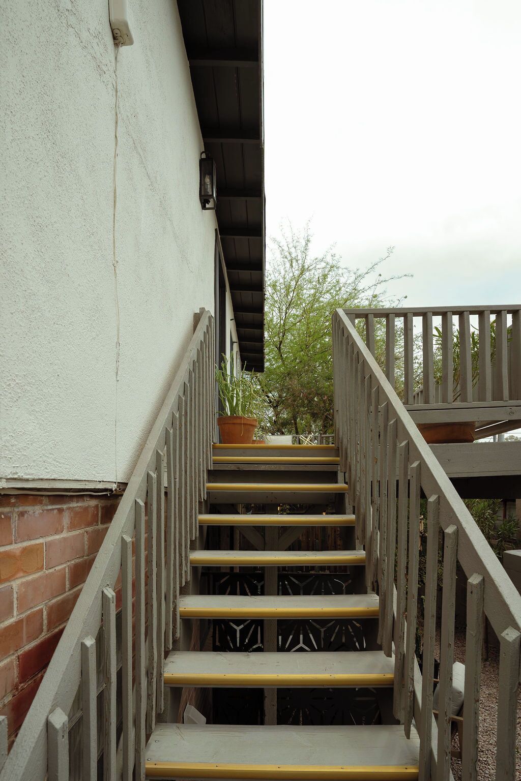Un escalier en bois avec une rampe en métal, menant à une terrasse.