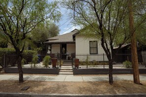 A residential house with a front porch, a garage, and a fenced yard. - The Sonora House – Entire Home (Tucson)