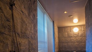 A modern bathroom with a stone wall, a bathtub, and a shower area.