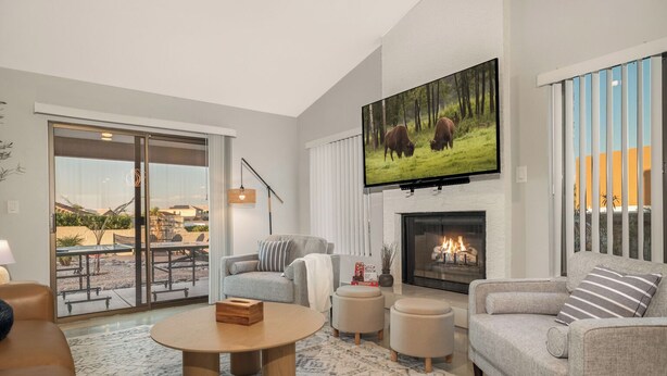 A modern living room with a fireplace, a flat-screen TV, and a sliding glass door leading to an outdoor patio.