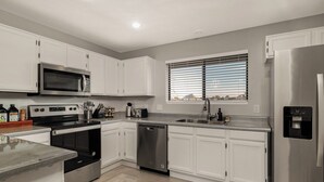 A modern kitchen with white cabinets, stainless steel appliances, a built-in microwave, a dishwasher, and a water dispenser.