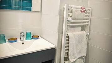 Un baño moderno con un lavamanos, espejo y toallero blancos.