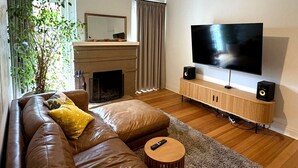Een moderne woonkamer met een leren bank, een televisie en speakers.