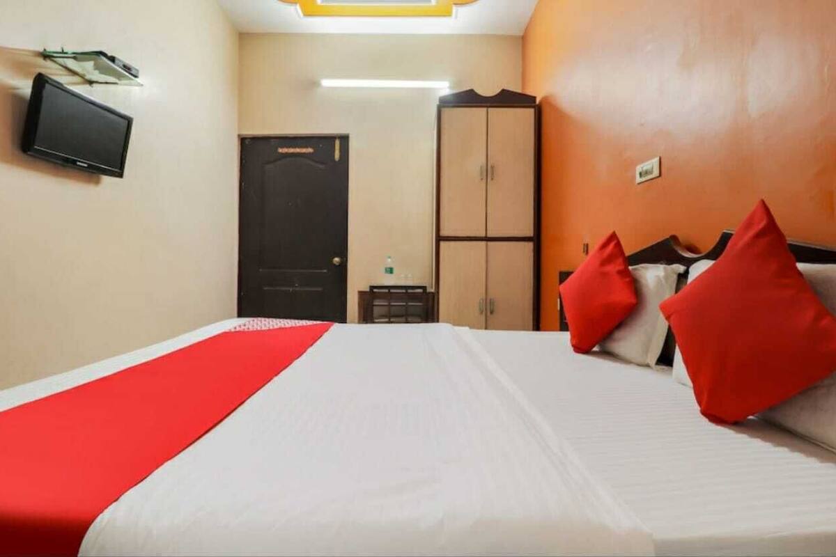 A hotel room with a bed, a wardrobe, a television, and a door.