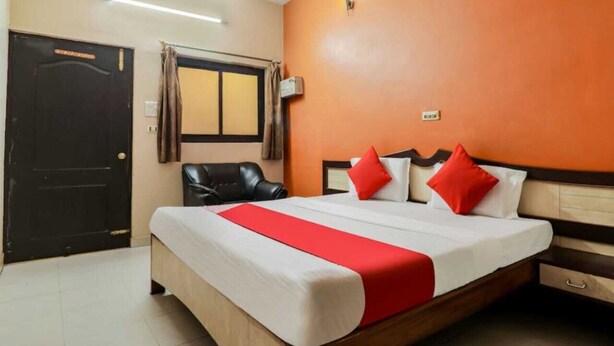 A hotel room with a bed, a chair, a wardrobe, and a window with curtains. - Hotel Sunrise Lucknow  (Lucknow)