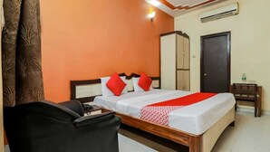 A hotel room with a bed, a chair, a wardrobe, and an air conditioning unit. - Hotel Sunrise Lucknow  (Lucknow)