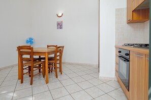Une cuisine équipée d’une table et de chaises, d’un ventilateur, d’une cuisinière et d’un petit luminaire fixé au mur.
