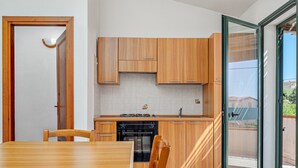 Una cocina moderna con armarios de madera, una mesa de comedor y un amplio ventanal corredizo a un espacio exterior.