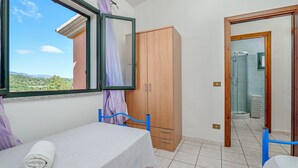 Un dormitorio con cama, un armario de madera, un baño con ducha y vistas al exterior.