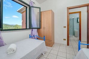 Un dormitorio con cama, un armario de madera, un baño con ducha y vistas al exterior.