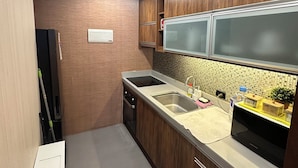 A compact kitchen with wooden cabinets, a stainless steel sink, and a built-in microwave.