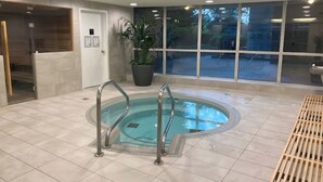 A swimming pool with metal railings, a wooden bench, and a potted plant.