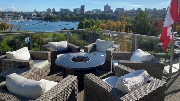 A terrace with wicker furniture, a round table, and a flag.