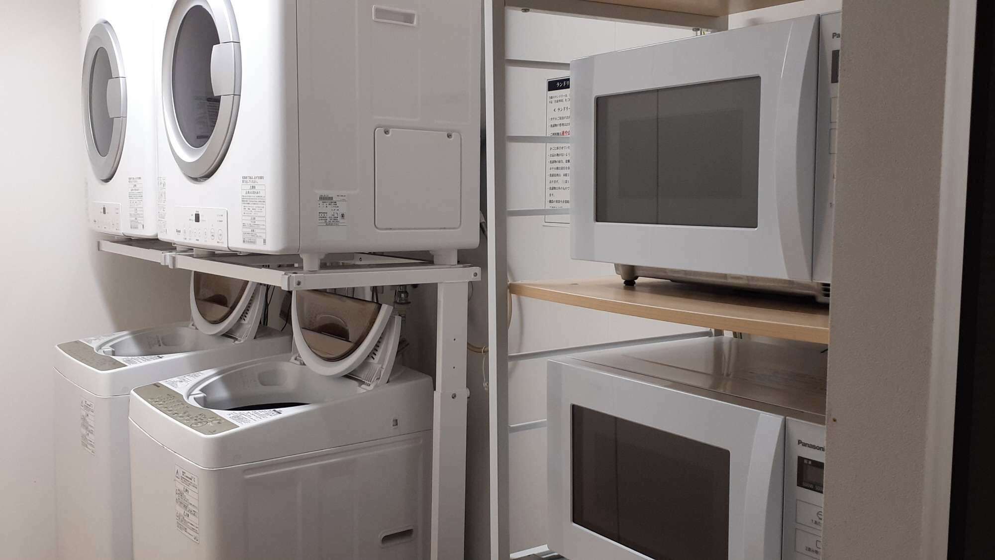 Une buanderie équipée d’une pile de machines à laver et de sèche-linge, d’un four à micro-ondes et d’une étagère sur laquelle se trouve un appareil Panasonic.