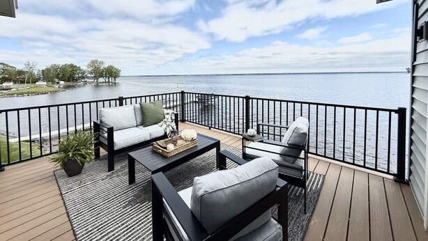 A deck with outdoor furniture, a potted plant, and a view of the water.