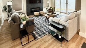 A modern living room with a fireplace, a sofa, a coffee table, and a TV.