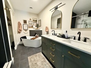 A modern bathroom with a freestanding bathtub, a large vanity with dual sinks, and a mirror above the vanity. - Huge 6BR Oneida Lakefront Retreat - Sleeps 20! (Cicero)