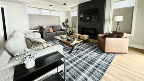 A modern living room with a sofa, a coffee table, and a fireplace. - Huge 6BR Oneida Lakefront Retreat - Sleeps 20! (Cicero)