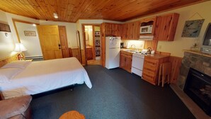 Habitació petita amb llit, cuineta i llar de foc.