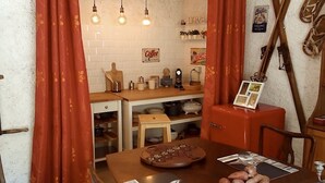 Una cocina con una mesa de madera, un armario rojo y bombillas colgantes.