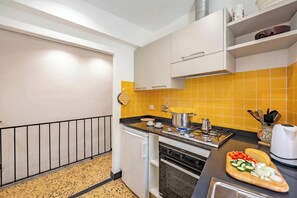A modern kitchen with a gas stove, oven, and a yellow-tiled backsplash. - Charming Apartment With Balcony In Vernazza (Vernazza)