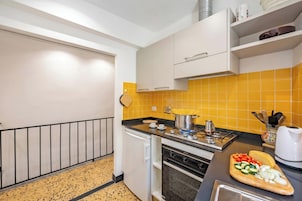 Uma cozinha moderna com fogão a gás, forno e painel atrás do fogão com azulejos amarelos.